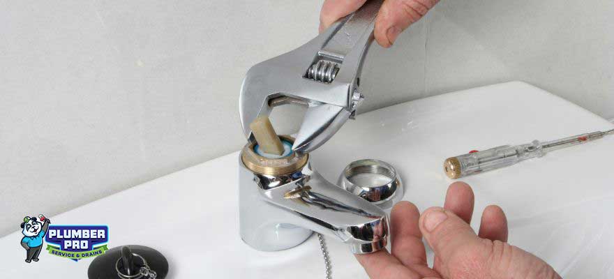 A professional plumber doing faucet repair in a modern bathroom in Lawrenceville, GA.