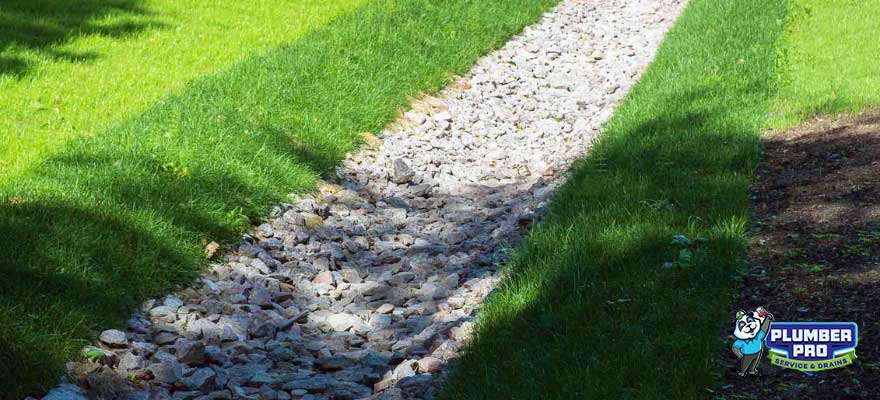 A professional installing a French drain system in Lawrenceville, GA. The image shows a trench lined with gravel and a perforated pipe, with the installer ensuring proper water drainage.