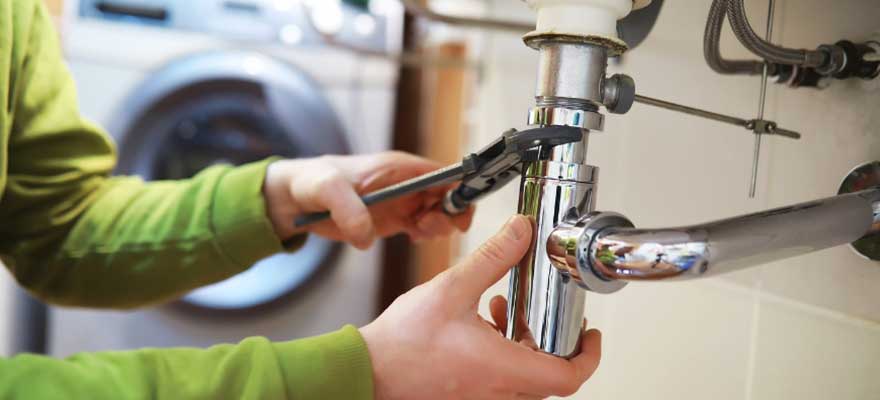 Plumber fixing pipes under a sink in Lawrenceville, GA.