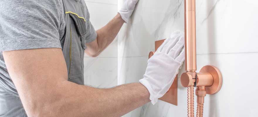 Professional plumber repairing a showerhead and faucet in a modern bathroom in Lawrenceville, GA. The plumber is using tools to fix leaks and improve water flow.